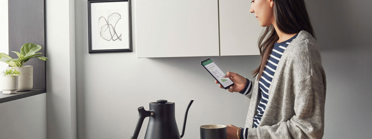 Woman drinking coffee while looking at phone